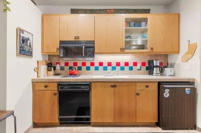 a kitchen with wooden cabinets and a black dishwasher at Palisades Tahoe Lodge Rentals Studio #146 in Olympic Valley