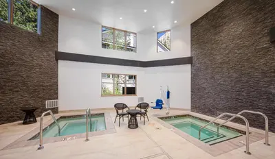 a swimming pool with a table and chairs in a building at Palisades Tahoe Lodge Rentals Studio #203 in Olympic Valley