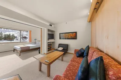 a living room with a couch and a table at Palisades Tahoe Lodge Rentals Studio #147 in Olympic Valley