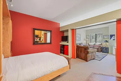 a bedroom with a red wall with a bed and a mirror at Palisades Tahoe Lodge Rentals Studio #151 in Olympic Valley