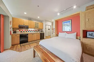 a bedroom with a large bed and a kitchen at Palisades Tahoe Lodge Rentals Studio #151 in Olympic Valley