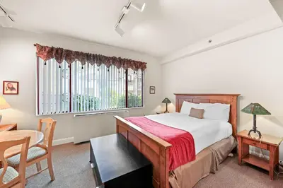 a bedroom with a bed and a desk and a window at Palisades Tahoe Lodge Rentals Studio #154 in Olympic Valley