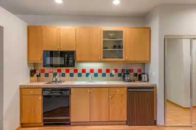 a kitchen with wooden cabinets and a sink and a microwave at Palisades Tahoe Lodge Rentals Studio #158 in Olympic Valley
