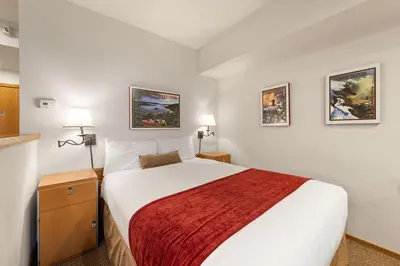 a bedroom with a large bed with a red blanket at Palisades Tahoe Lodge Rentals Studio #205 in Olympic Valley