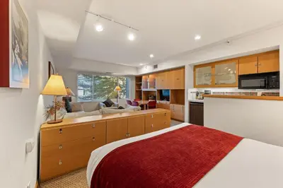 a bedroom with a bed and a couch and a kitchen at Palisades Tahoe Lodge Rentals Studio #205 in Olympic Valley