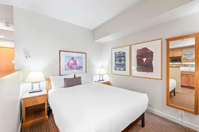 a hotel room with a white bed and a mirror at Palisades Tahoe Lodge Rentals Studio #215 in Olympic Valley