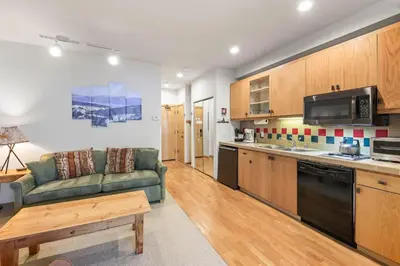 a living room with a couch and a kitchen at Palisades Tahoe Lodge Rentals Studio #248 in Olympic Valley