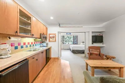 a kitchen with a table and a room with a bed at Palisades Tahoe Lodge Rentals Studio #248 in Olympic Valley
