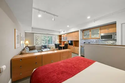 a bedroom with a bed and a kitchen with a couch at Palisades Tahoe Lodge Rentals Studio #226 in Olympic Valley