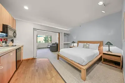 a bedroom with a white bed and a kitchen at Palisades Tahoe Lodge Rentals Studio #247 in Olympic Valley
