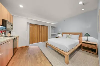 a bedroom with a white bed and a kitchen at Palisades Tahoe Lodge Rentals Studio #247 in Olympic Valley