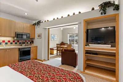 a room with a bed and a kitchen with a television at Palisades Tahoe Lodge Rentals Studio #253 in Olympic Valley