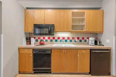 a kitchen with wooden cabinets and a sink and a microwave at Palisades Tahoe Lodge Rentals Studio #255 in Olympic Valley