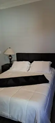 a bed with white sheets and a black headboard at Roseville Properties in Roseville