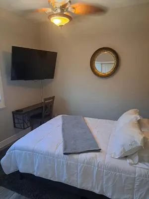 a bedroom with a bed with a ceiling fan and a mirror at Roseville Properties in Roseville