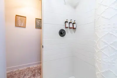 a shower in a bathroom with a white wall at Riverside Luxe: Stylish Designer Retreat in Reno