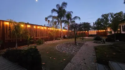 a backyard with a fence with lights on it at ¤ Old Folsom La Boheme Artist Retreat + Jacuzzi ¤ in Folsom
