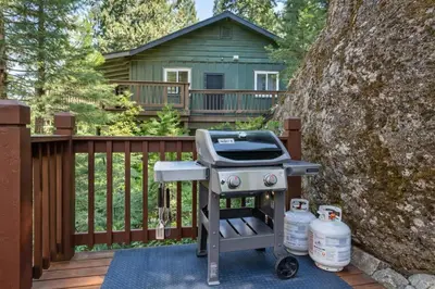 a grill on a deck with a house in the background at Lewis Creek cabin near Yosemite king beds in Oakhurst