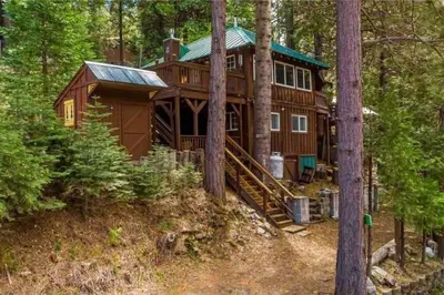 a large wooden cabin in the woods with trees at Lewis Creek cabin near Yosemite king beds in Oakhurst