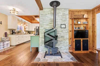 a living room with a stone fireplace in a kitchen at Sugar Pine cabin in the woods King bed Fire pit in Oakhurst