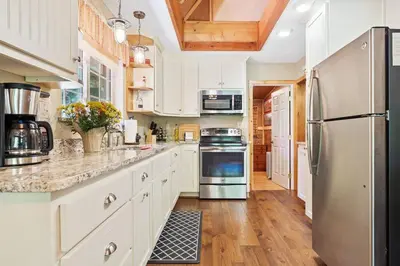 a kitchen with white cabinets and a stainless steel refrigerator at Sugar Pine cabin in the woods King bed Fire pit in Oakhurst