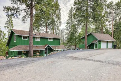 a green house with a driveway in front of it at Cozy Mi-Wuk Village Cabin 18 Mi to Dodge Ridge! in Mi-Wuk Village