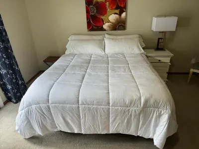 a bed in a bedroom with a white bedspread at Meadow Landing in Three Rivers