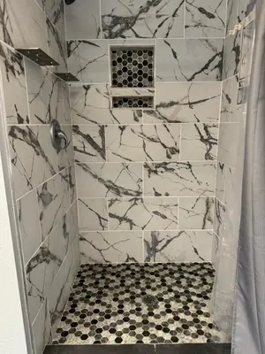 a bathroom with a shower with a black and white tiles at Meadow Landing in Three Rivers