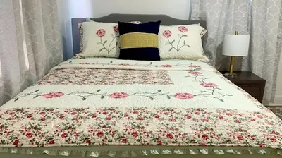 a bed with a floral comforter and pillows at Beautiful Spanish-Styled Home in Fresno