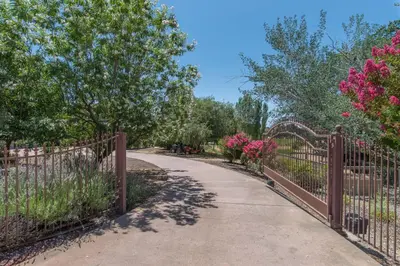 a walkway through a fence with pink flowers at Master Suite Fraser Family Vineyard Stay in Amador in Plymouth