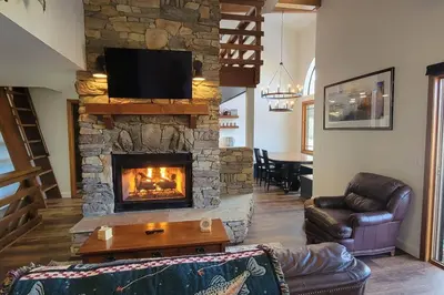 a living room with a stone fireplace with a television at Lakefront Mountain Retreat in June Lake