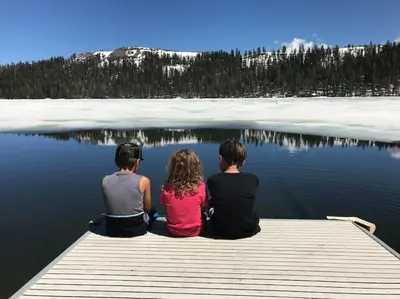 two children sitting on a dock on a lake at Big Cabin on the Creek in Camp Connell