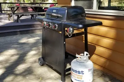 a black barbecue grill with a bucket next to a house at Mountain Life On Deck in Arnold