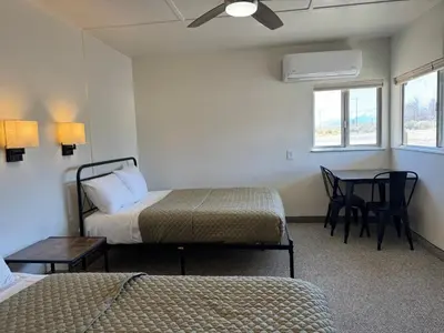 a room with two beds and a table with chairs at Eastern Sierra Motor Lodge in Independence