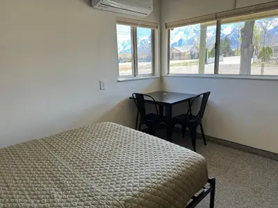 a bedroom with a bed and a table and windows at Eastern Sierra Motor Lodge in Independence