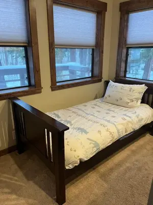 a small bed in a room with three windows at Cabin in the Woods in Tahoe Vista