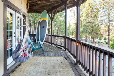 a porch with a hammock and a surfboard on it at Enchanted Woodland Cabin Near Yosemite with Fire Pit in Groveland