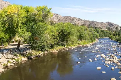 a river with rocks and trees and mountains in the background at Brand New Cabin in Kernville