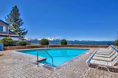 a swimming pool with lounge chairs next to a house at Lakeland Village 406 - The Lake Escape in South Lake Tahoe