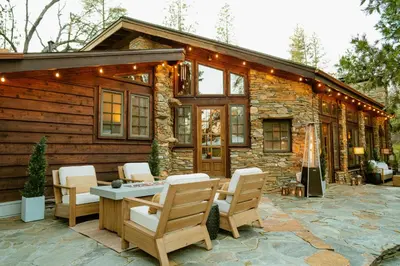a log cabin with a table and chairs on a patio at Luxury Nature Getaway Stone House by Casa Oso in Mariposa
