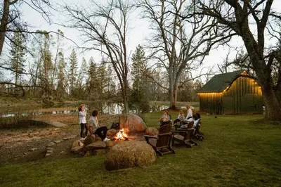 a group of people sitting around a fire in a yard at Luxury Nature Getaway Stone House by Casa Oso in Mariposa