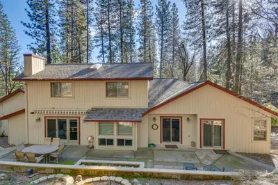 a house with a patio in the woods at Gas Grill and Pool Table Cabin Near Calaveras Park! in Arnold
