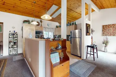 a kitchen with a stainless steel refrigerator and wooden ceilings at Yard and Patio Quiet and Well-Stocked Riverside Home in Three Rivers