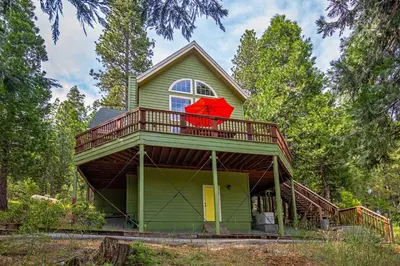 a green house with a red umbrella on the balcony at Anderson's Alpine Retreat- Pinecrest, CA Dodge Ski in Cold Springs