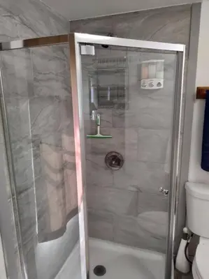 a shower with a glass door in a bathroom at Campground at Sequoia Mountain Farms - Bring Your Own Tent or RV - No Bedrooms or Beds Provided in Miramonte