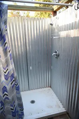 a shower with a curtain in front of a fence at Campground at Sequoia Mountain Farms - Bring Your Own Tent or RV - No Bedrooms or Beds Provided in Miramonte