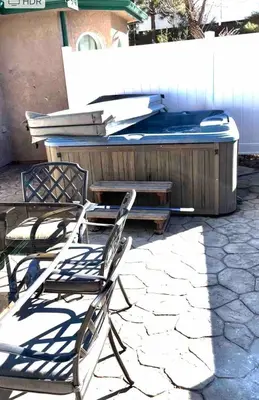 a hot tub sitting next to a table and chairs at Peacock House Sleeps 12 Hot Tub Game Room in Ahwahnee