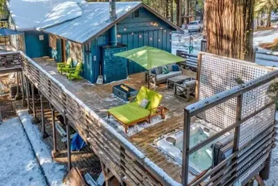 a blue tiny house with a deck with a bench and umbrella at Starlight Cabin in Oakhurst