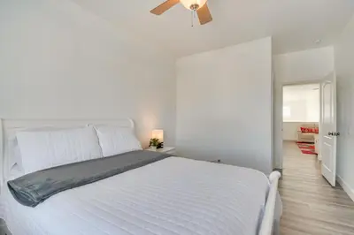 a white bed in a white bedroom with a ceiling fan at 4 Mi to Dtwn Merced Spacious Home with Yard! in Merced
