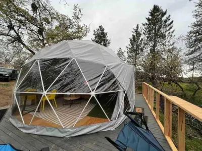 a tent on a deck with a table and chairs at Enchanted Forest Dome ,10-15 minutes to Kings Canyons-New pellet stove for cozy warm nights in Dunlap